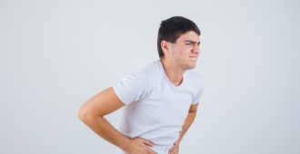 young male in t-shirt suffering from stomachache and looking painful , front view.