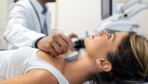 Close up shot of young woman getting her neck examined by doctor using ultrasound scanner at modern clinic